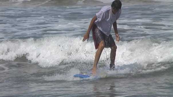 Saska belajar surfing, berdiri di atas papan di ombak kecil